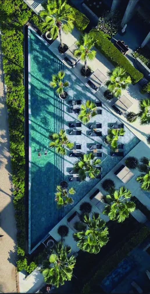 Aerial view of the podium-level resort swimming pool with palm decking at Hero Homes Sector MU